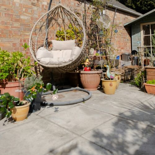 Single woven hanging egg chair on a concrete outdoor space